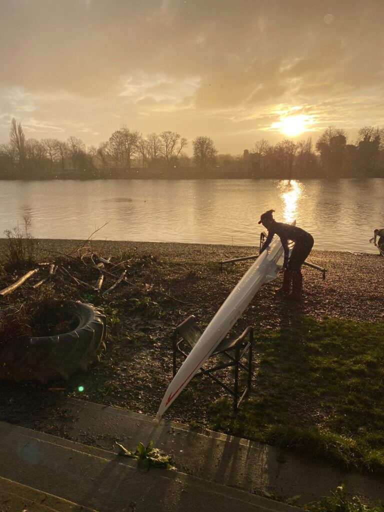 Woman lifting scull boat on the bank of the Thames